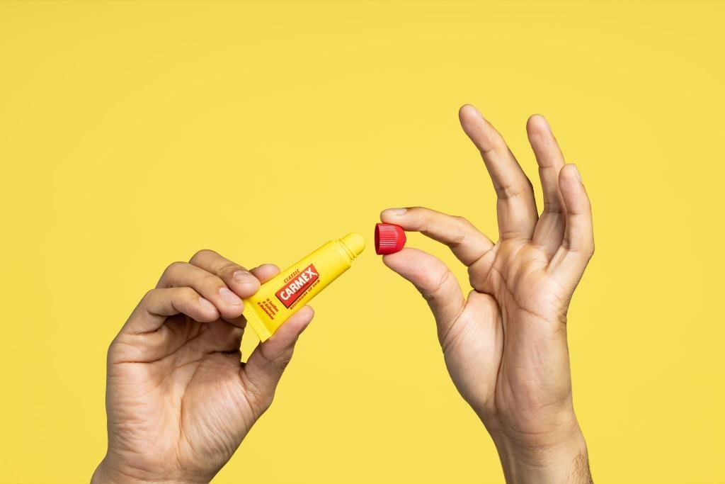 Hands with Carmex lip balm tube and cap